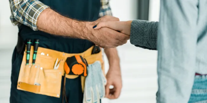 cropped image of plumber and customer shaking hands in kitchen