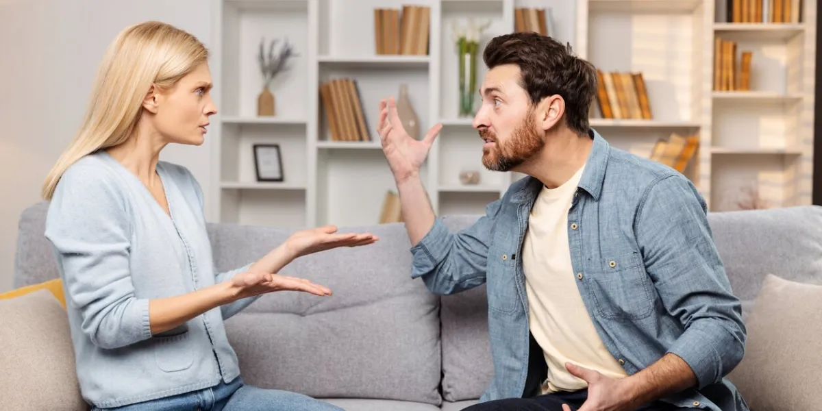emotional support for abused families depicted  an enraged husband raises his hand against his wife on their couch, poised to strike