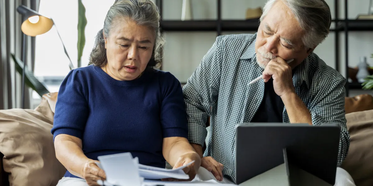 serious stressed asian senior old couple worried about bills discuss unpaid bank debt paper, sad poor retired family looking at tablet counting loan payment worry about money problem