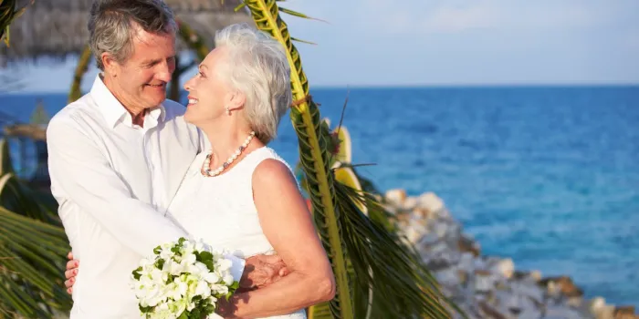 senior couple getting married in beach ceremony looking at each other smiling