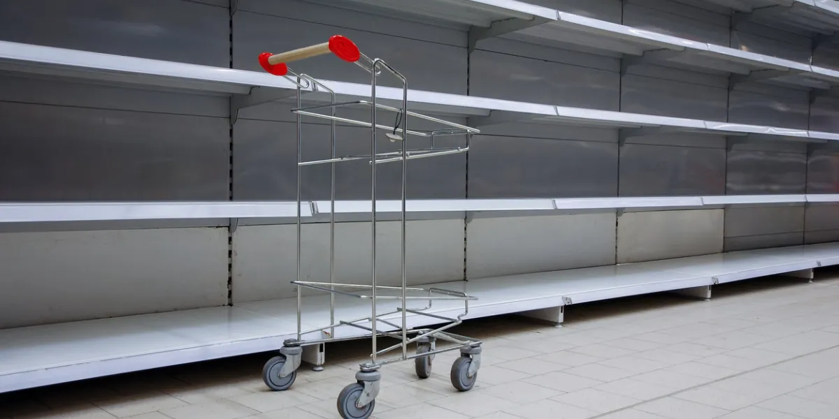 empty shelves and shopping cart in supermarket, all sold out due to panic caused by virus outbreak
