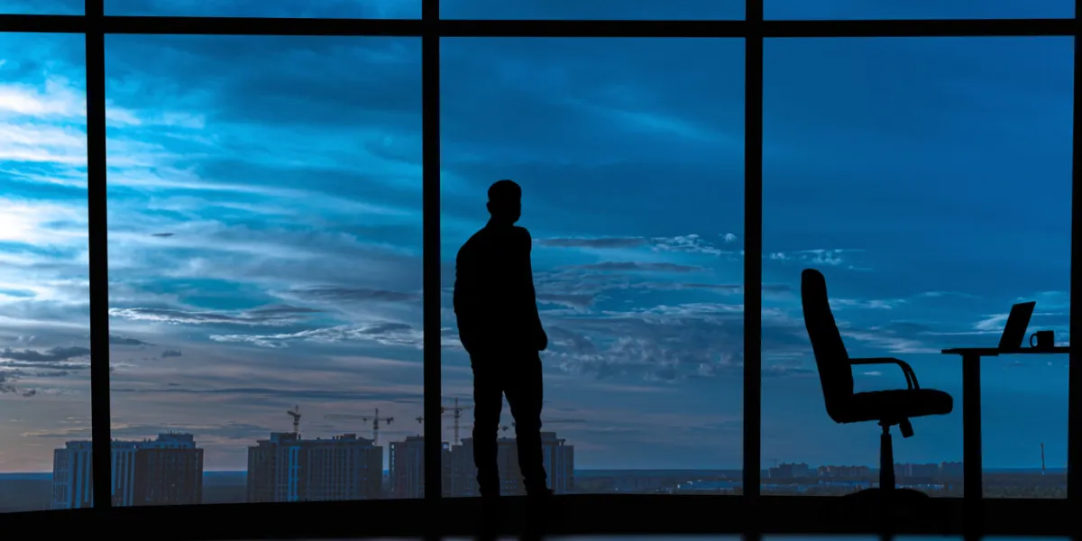 the businessman is standing near the windows in the office center