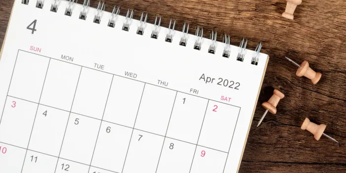top view calendar desk 2022 on april month, the concept of planning and deadline with push pin on wooden table background