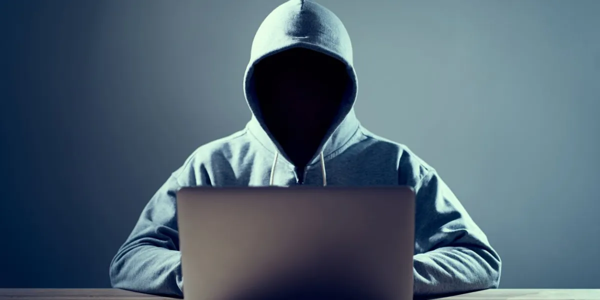 male hacker writing code on a laptop