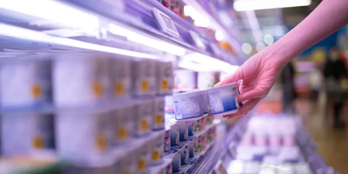 woman picking up yogurt in a supermarket