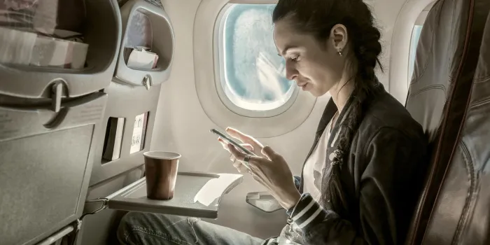 femme assise à l'avion et à la recherche sur le téléphone mobile