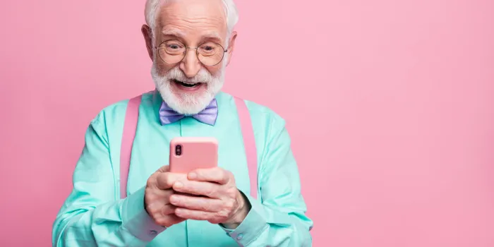 portrait of surprised crazy shocked old man use smartphone read, social media news enjoy comments wear teal outfit purple violet bow tie isolated pastel pink color background