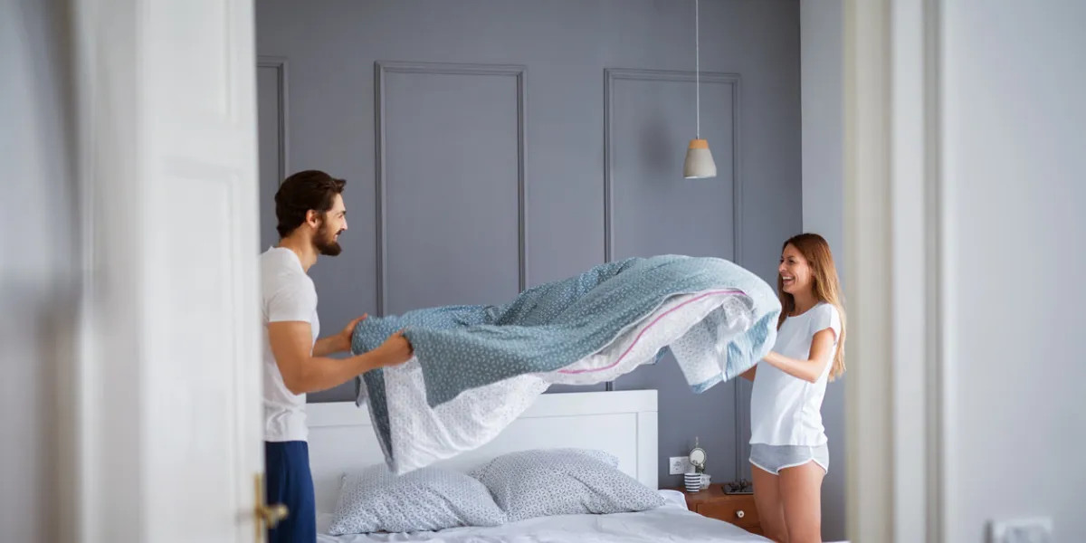 charming beautiful couple in love making the bed together and having fun