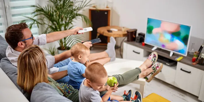 young parents watching tv with baby boys