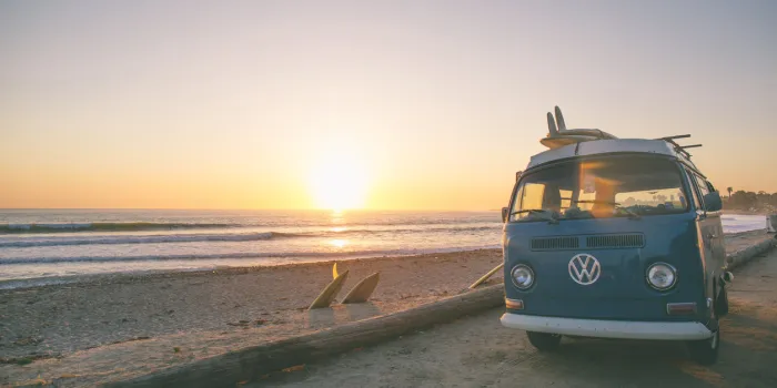 san onofre, ca, usa - april 10, 2017  a current but timeless image of a 60's vw bus, parked at san onofre surf beach single fin classic longboards liter the scenery as the surfers enjoy the waves in the fading light of the day