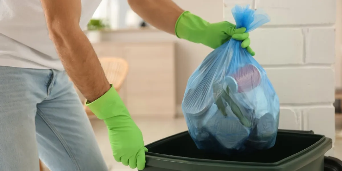 man throwing garbage bag into bin at home, closeup