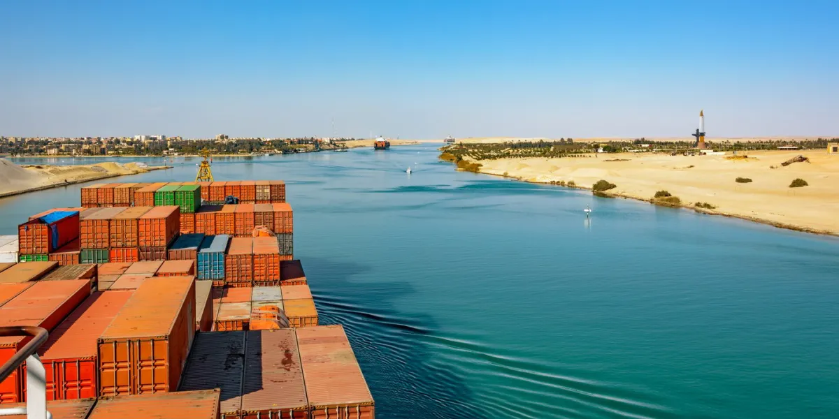 industrial container ship passing through suez canal with ship's convoy, view on the bow from the captain bridge