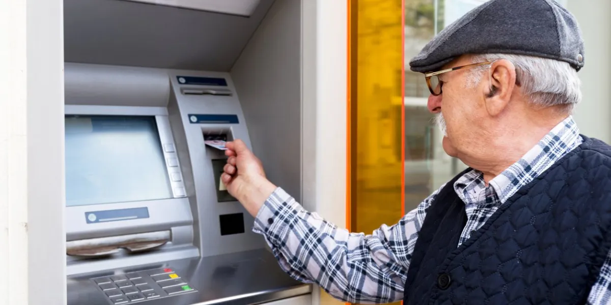 elderly man inserting credit card to atm outdoor