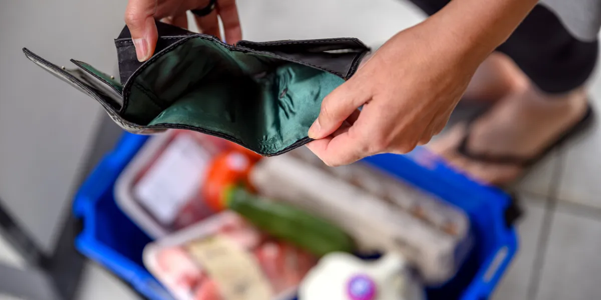 a woman ended up with an empty wallet after a basic grocery shopping before payday she is checking her purse, but she has no cash money or credit card left in it due to the high food price inflation