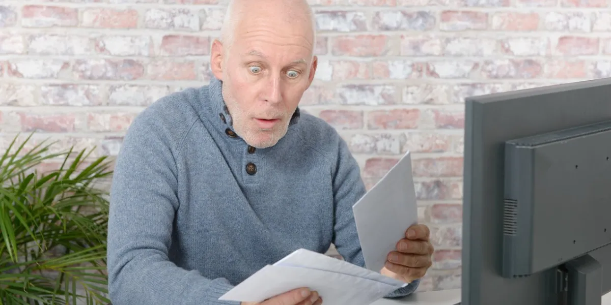mature businessman opening letter envelope, with astonishment