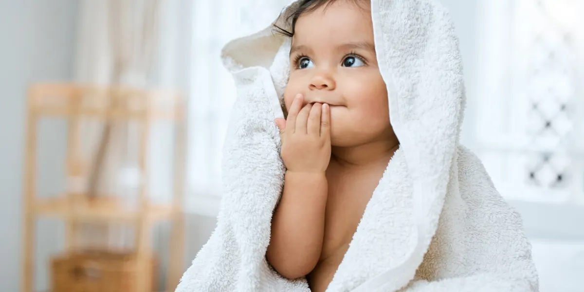 shot of an adorable baby covered in a towel after bath time