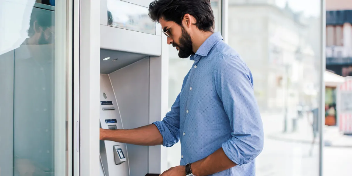 man using a street atm machine and withdrawing money