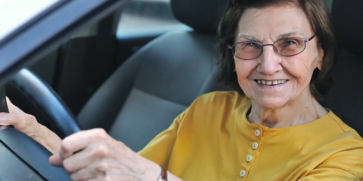active senior woman - smiling retired lady driving car, detail