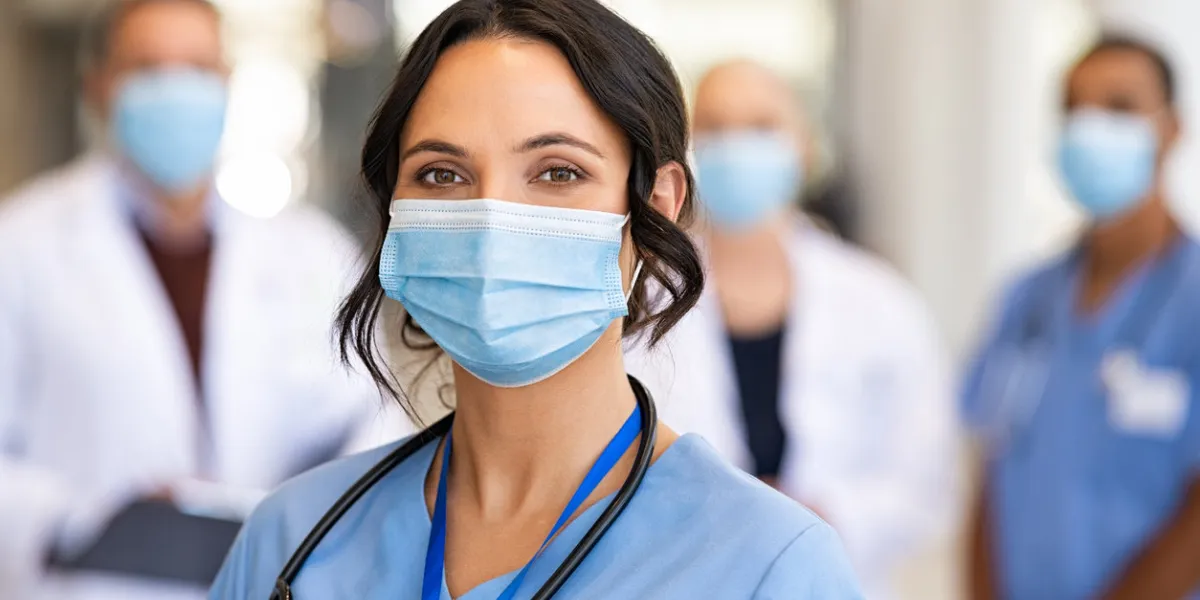 happy nurse with face mask smiling at hospital