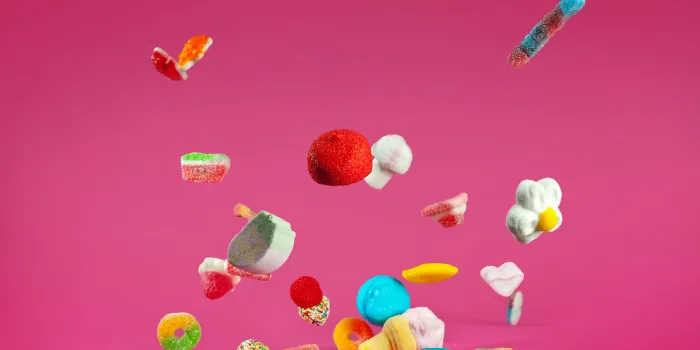 many colorful candies fall on a pink background sweets close up the concept of childhood and holidays copy space and free space for text near sweets