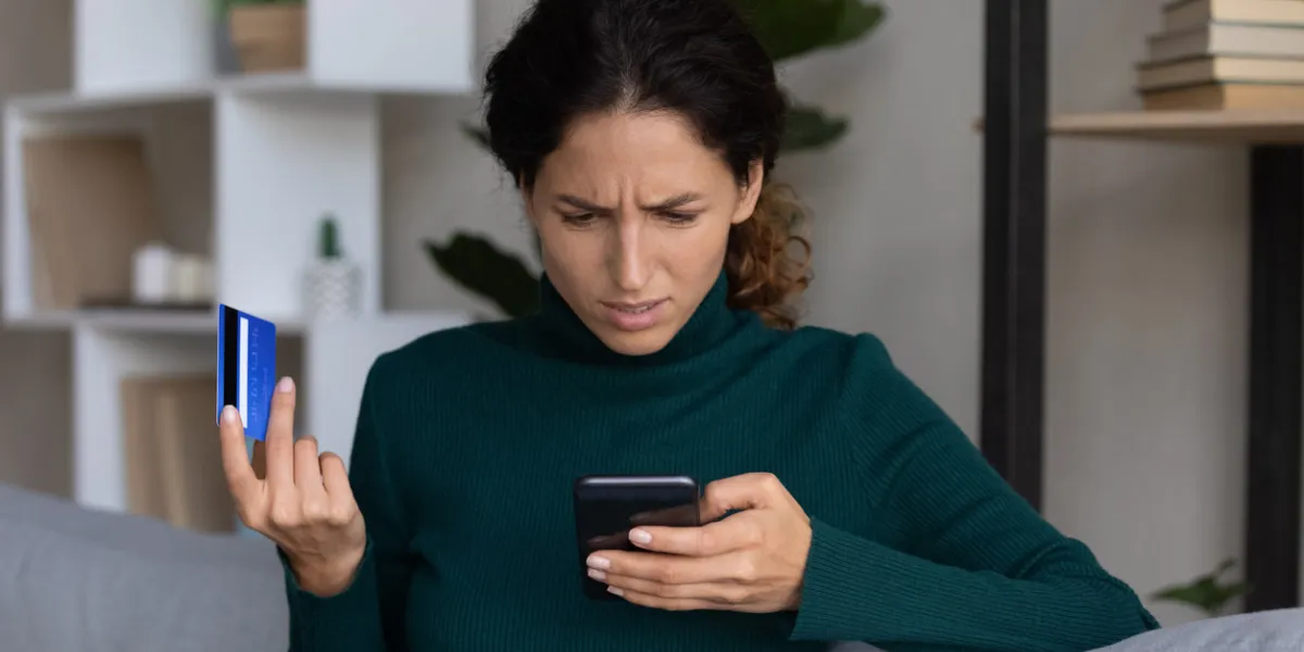 internet scam concerned young hispanic lady looking on smartphone screen having finance savings stolen from bank card as money fraud result upset nervous latin woman become online scammers victim