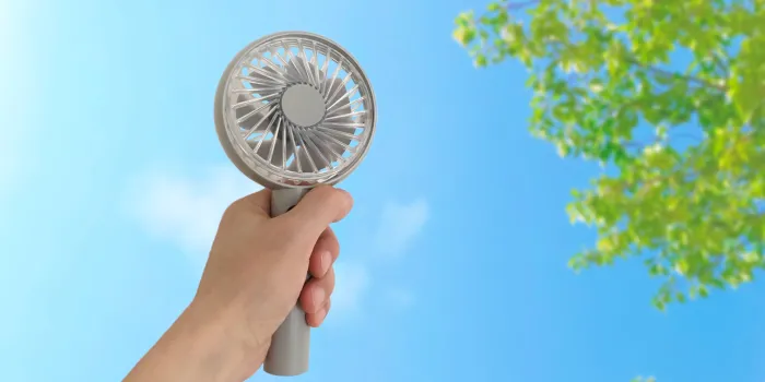 portable electric fan held in the left hand