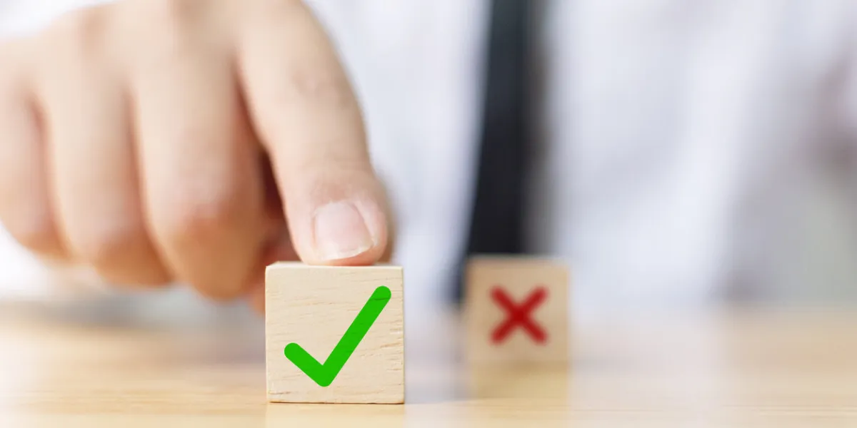 hand of a businessman chooses checkmark and x sign symbol on wooden cube block