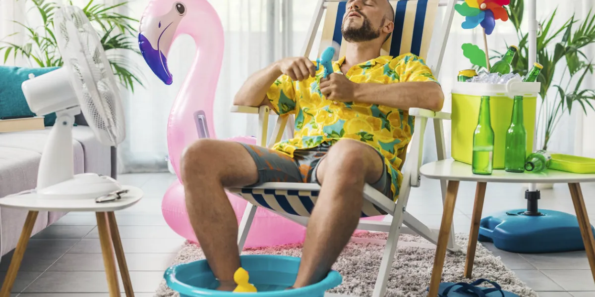 man spending summer vacations at home, he is cooling himself with electric fans and sitting on a deckchair