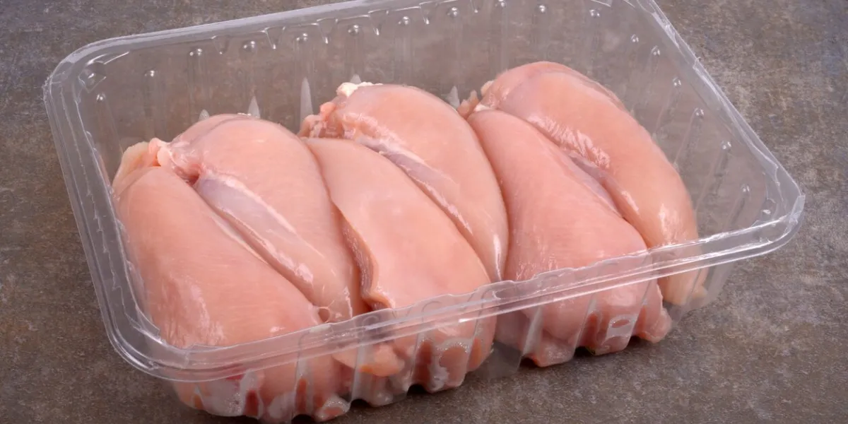 raw chicken fillets in close-up plastic packaging on a grey background