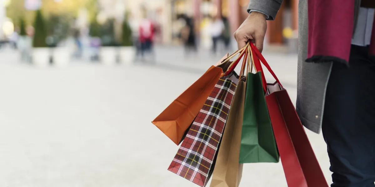 man holding shopping bags with presents on the street