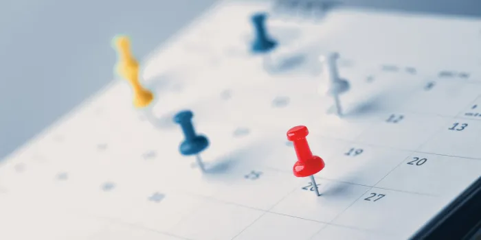 embroidered red pins on a calendar event planner calendar,clock to set timetable organize schedule,planning for business meeting or travel planning concept