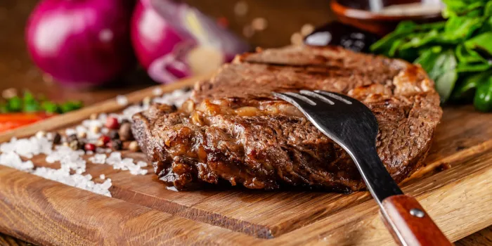 italian cuisine juicy beef meat, veal steak on a wooden board with spinach, prunes and french mustard sauce on the table is a glass of red pomegranate wine serving dishes in the restaurant