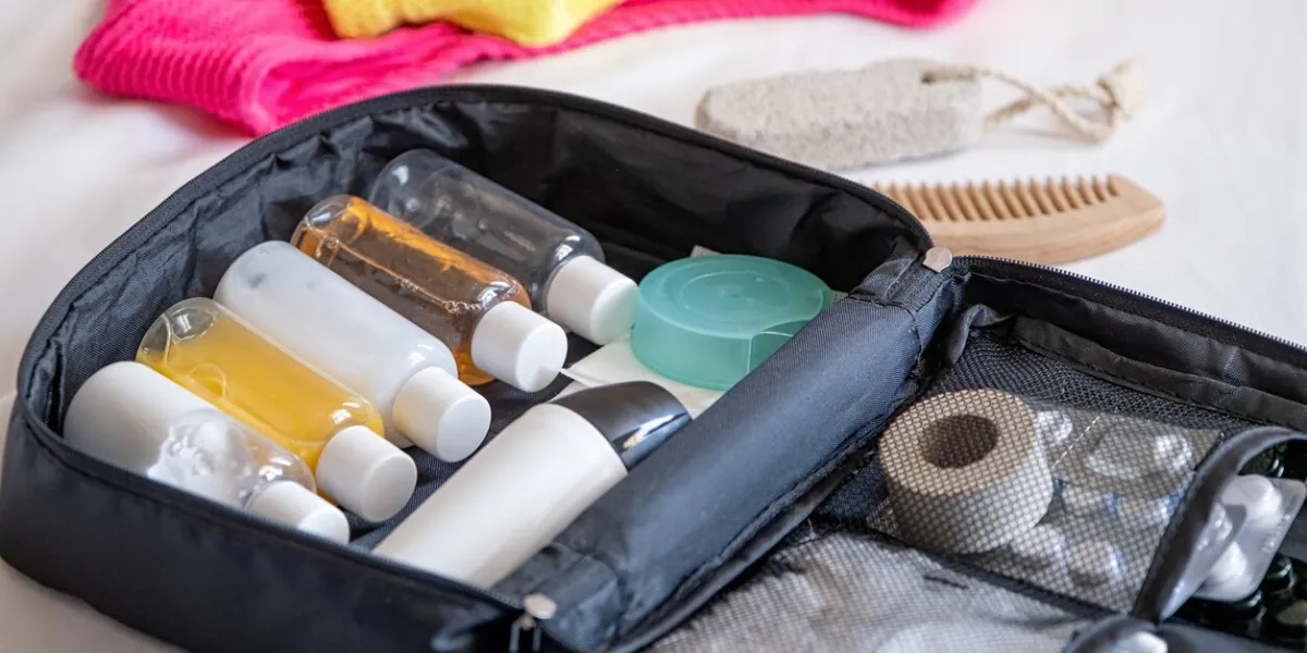 travel cosmetics kit with bottles, pills and cosmetics on bed