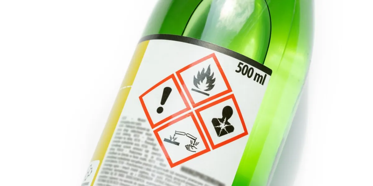 a green bottle of highly corrosive flammable chlorinated rubber nitro solvent with printed on warning symbols label, sticker dangerous chemical substances abstract concept, closeup, detail, nobody