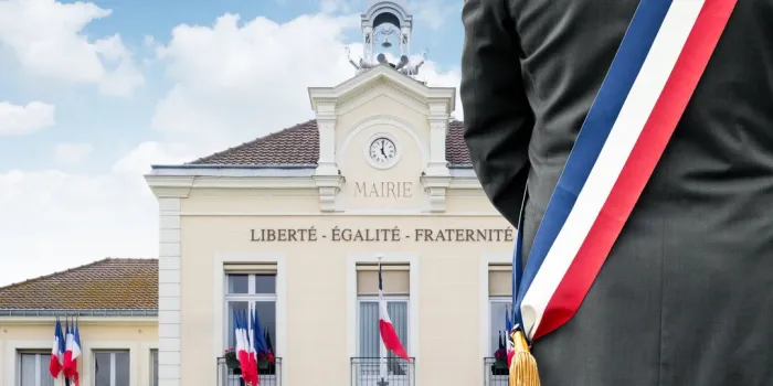 a mayor with his tricolor scarf in front of his town hall