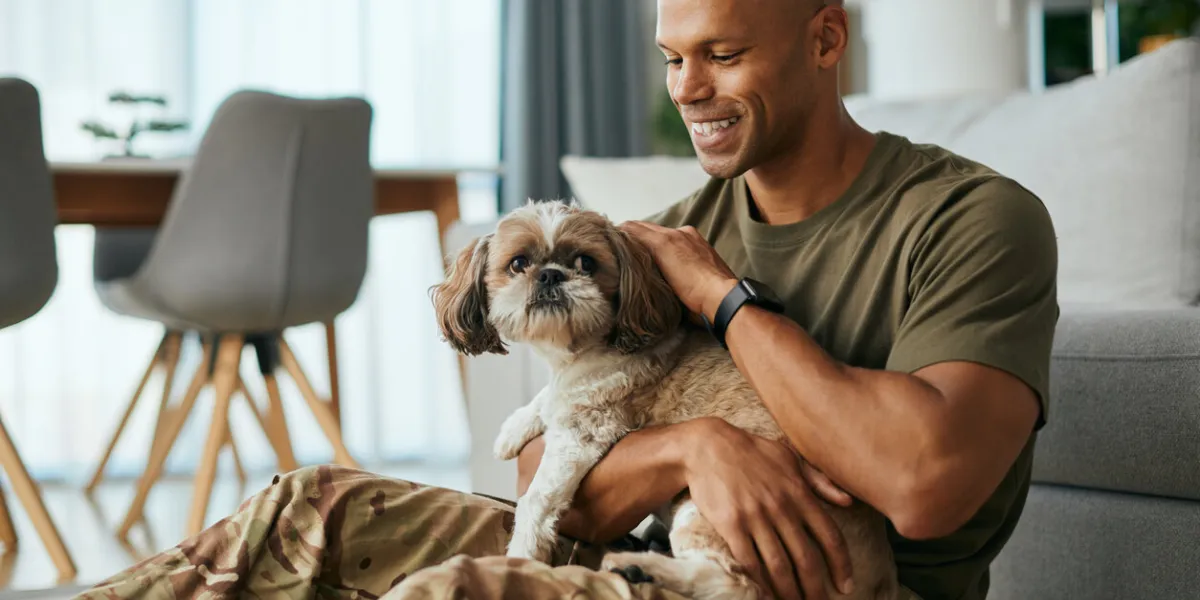 young african american soldier cuddling his dog while spending time together at home