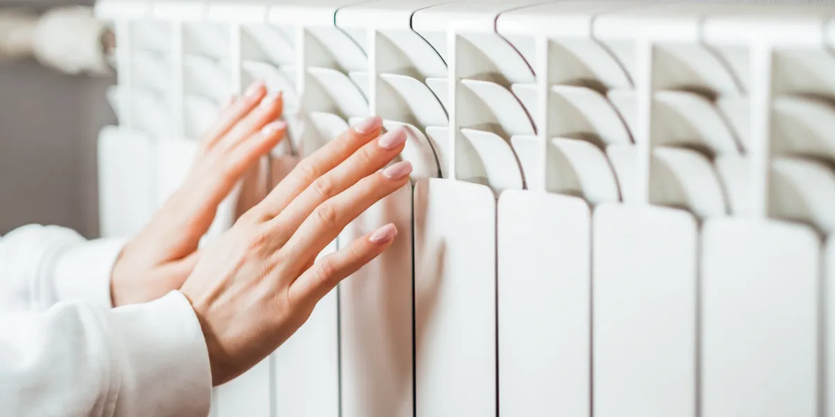 woman warms up hands over heater concept of the need for good central heating