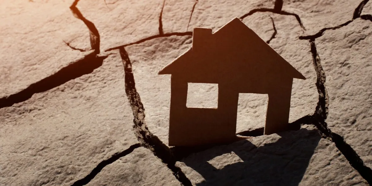 paper house on cracked earth, crisis concept