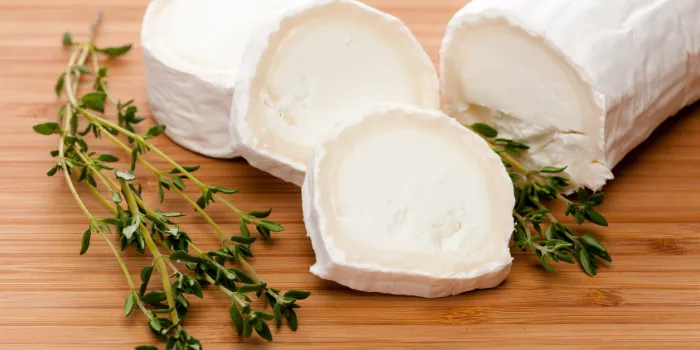 slices of goat cheese with fresh thyme on a bamboo cutting board