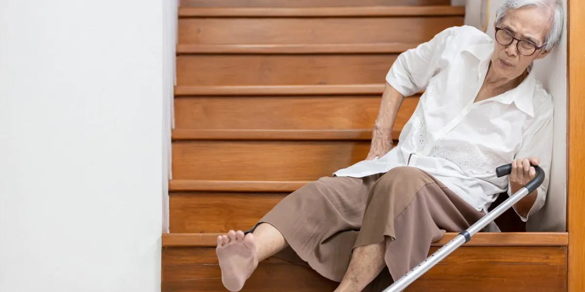 senior woman sitting on the floor of the staircase with pain in hips and back,tripped or lose balance as she walked downstairs causing accidents,old elderly slipped and fell was injured by dizziness