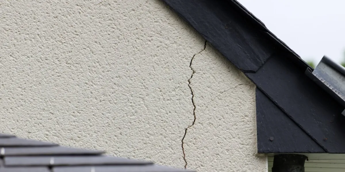 major crack in the plaster of a house wall just under the slate roof