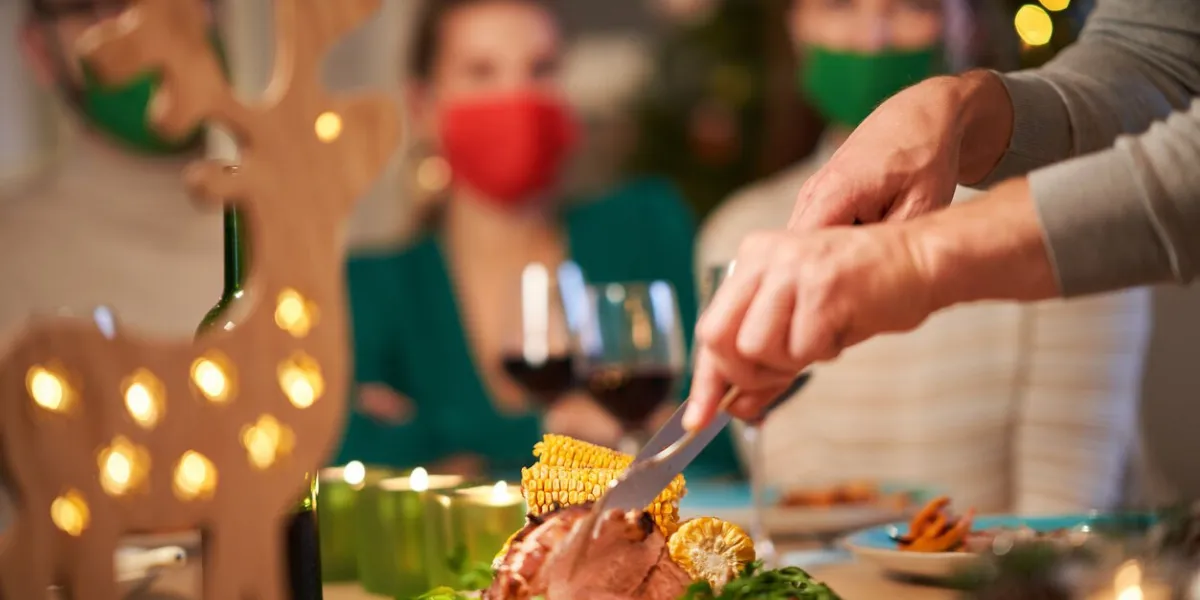 picture showing christmas ham being served on the table people wering masks in the background