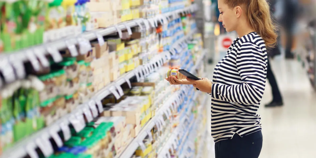 woman shopping in supermarket reading product information
