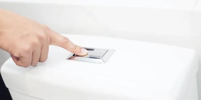 a man's hand pressing the power button toilet bowl