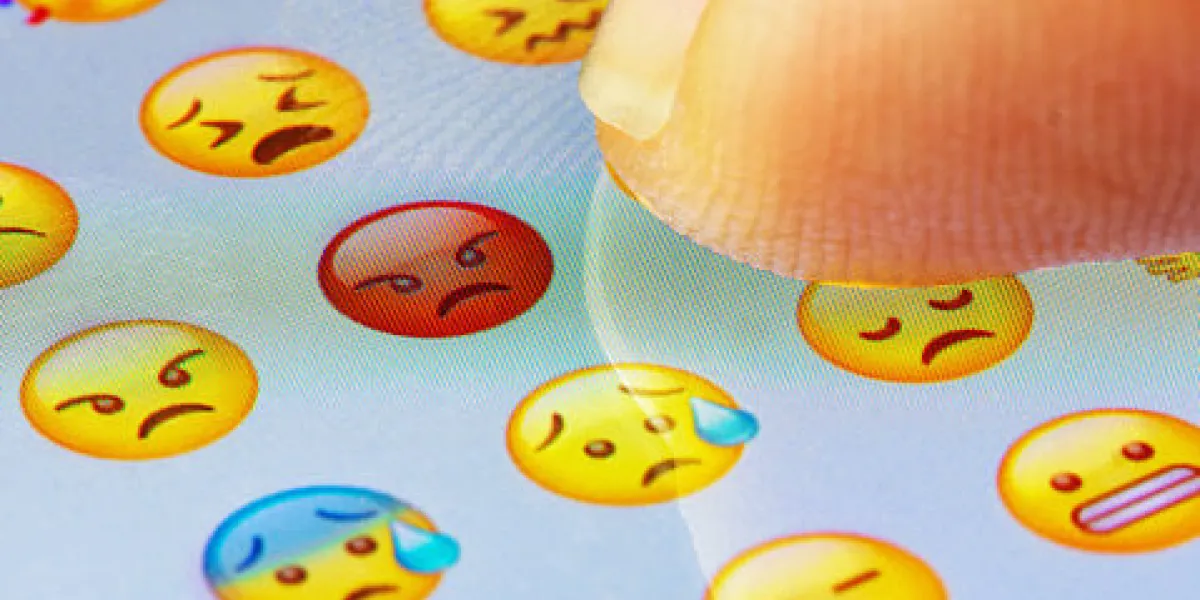 macro finger touching angry emoji on a virtual keyboard