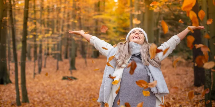 girl walking in the park in autumn and smiles with open arms