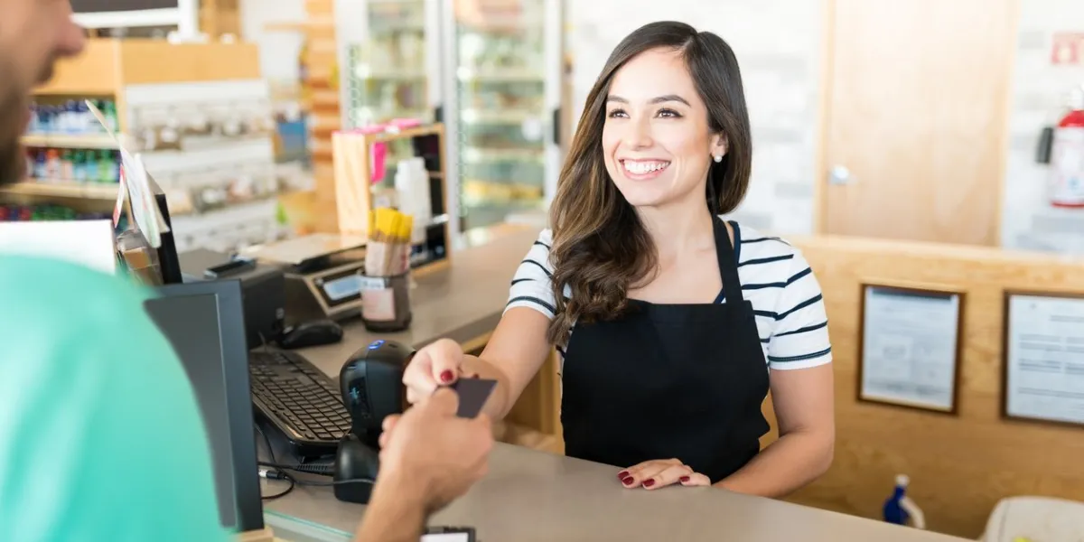 confident female cashier receiving payment through credit card in supermarket