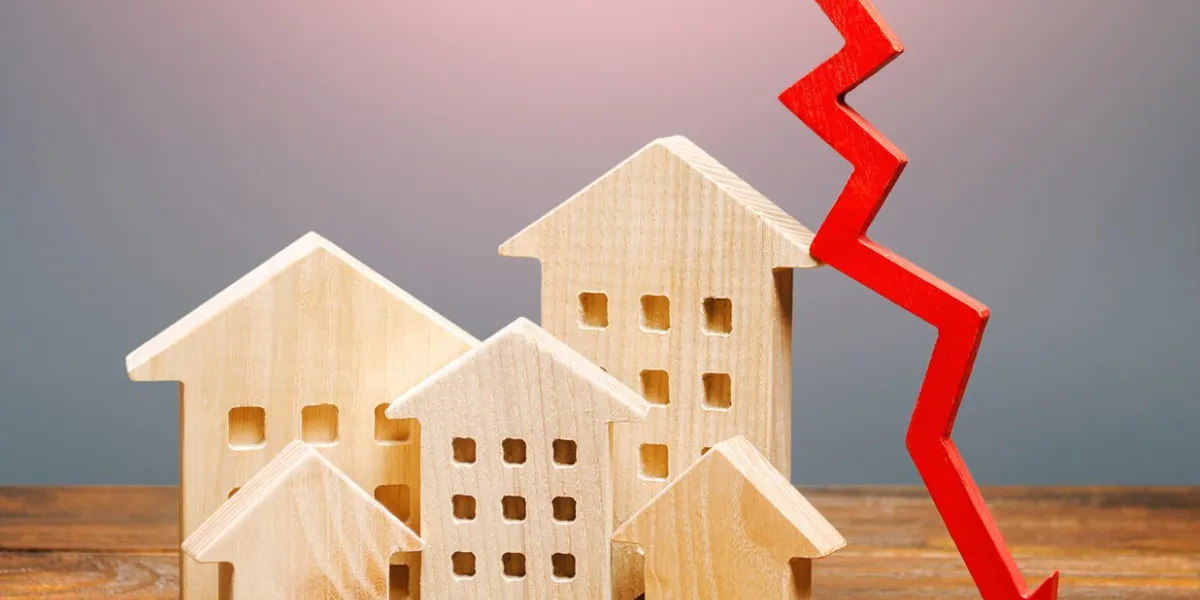 real estate houses and a red arrow down lower mortgage interest rates falling prices for rental apartments low demand for home buying market recession low liquidity, investment unattractiveness