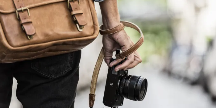 urban man photographer with leather bag in the city close-up hands