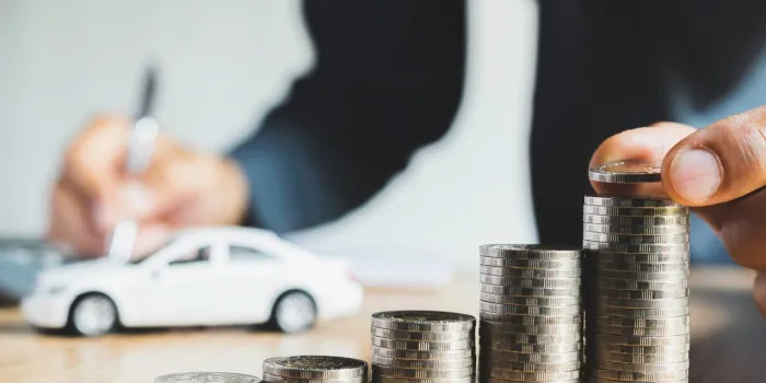 men are putting coin and saint documents about cars with some coins calculator and car toy on desk